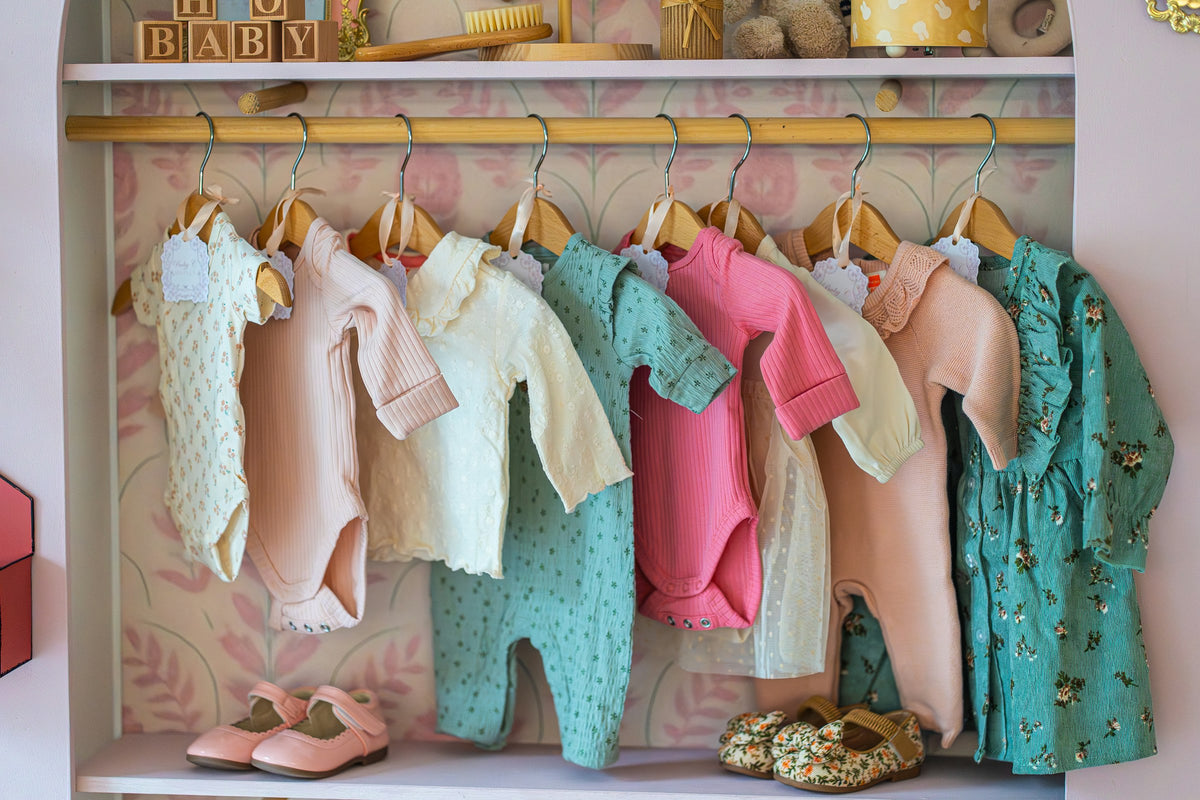 Soft pastel baby clothes on a nursery rail